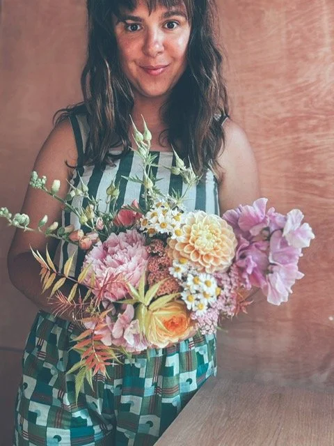 Ella holding a June bridal bouquet including dahlias, roses and cosmos.