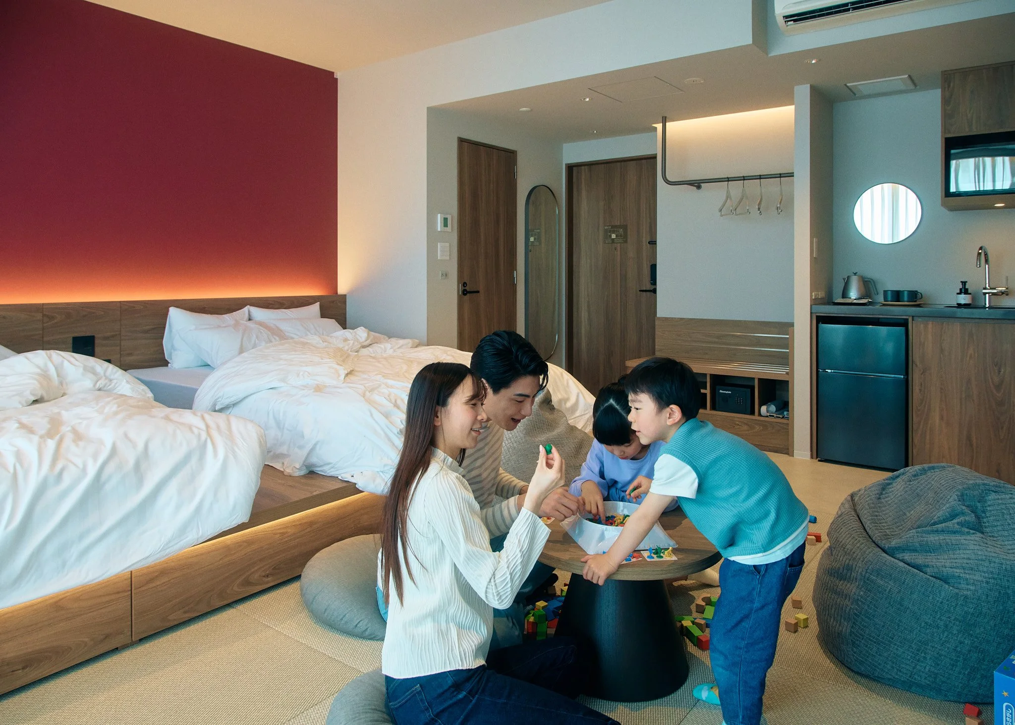 A family of four playing with building blocks in a modern hotel room