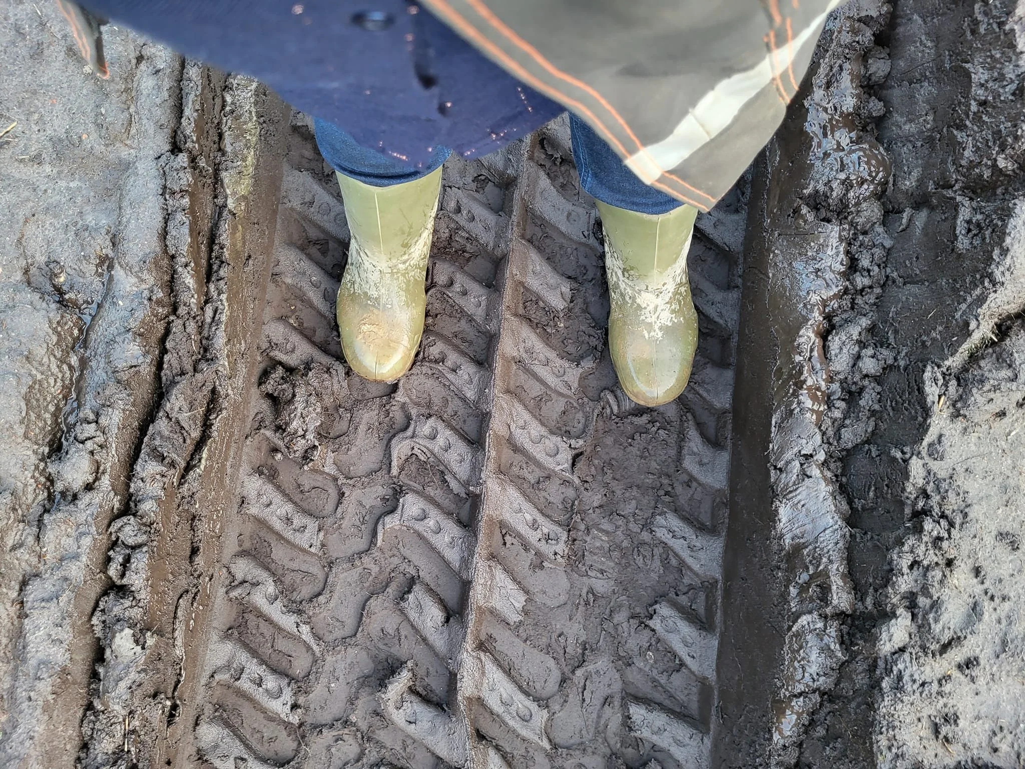 Elke Mertens, onafhankelijk archeologisch adviseur. Op de foto zijn enkel haar groene rubberen laarzen herkenbaar. Ze staat op modderige grond met sporen van een graafmachine zichtbaar.