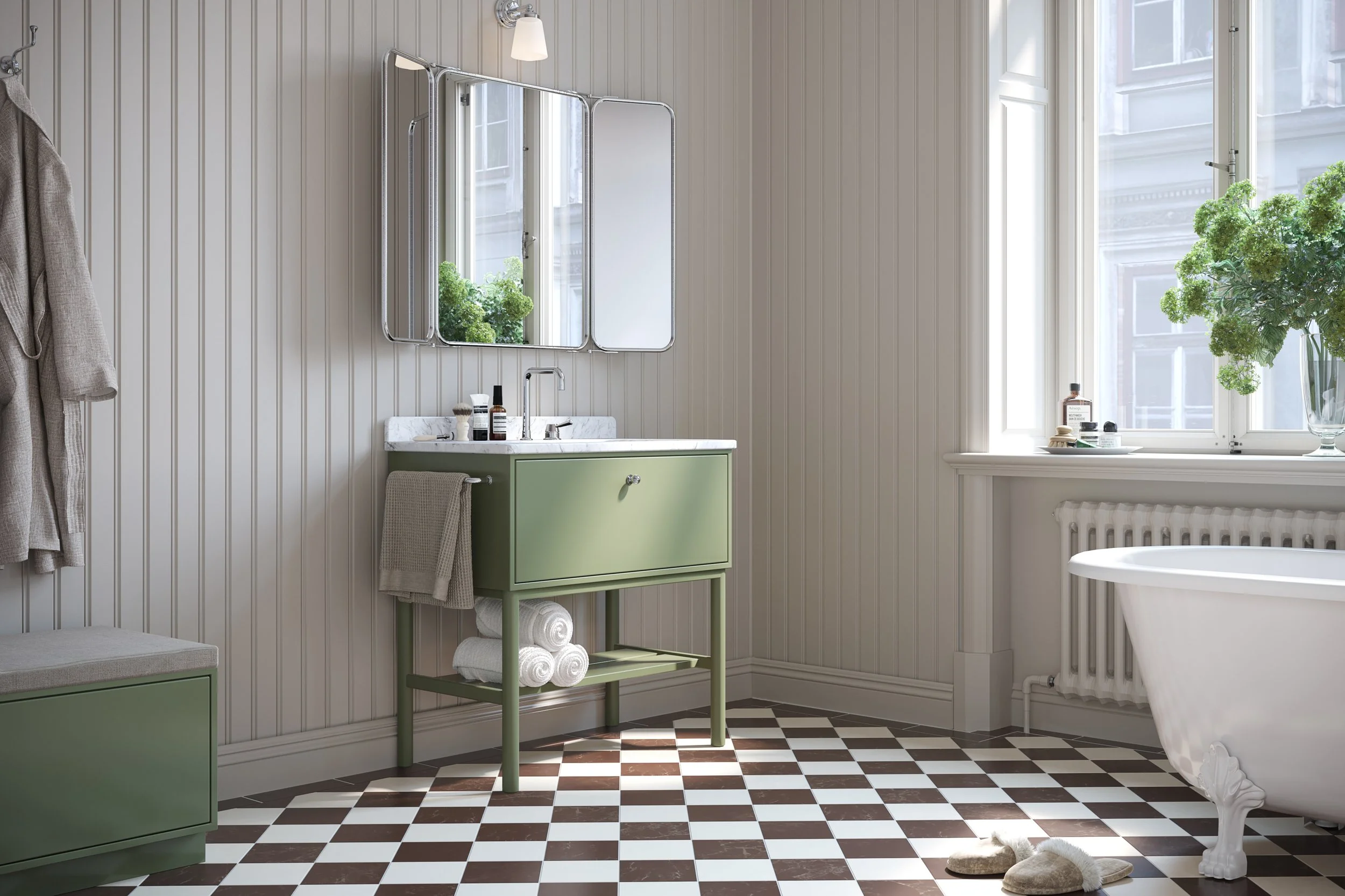 A cozy bathroom with a green vanity, a large window with a vase of green flowers, a clawfoot tub, and a checkered brown and white floor.