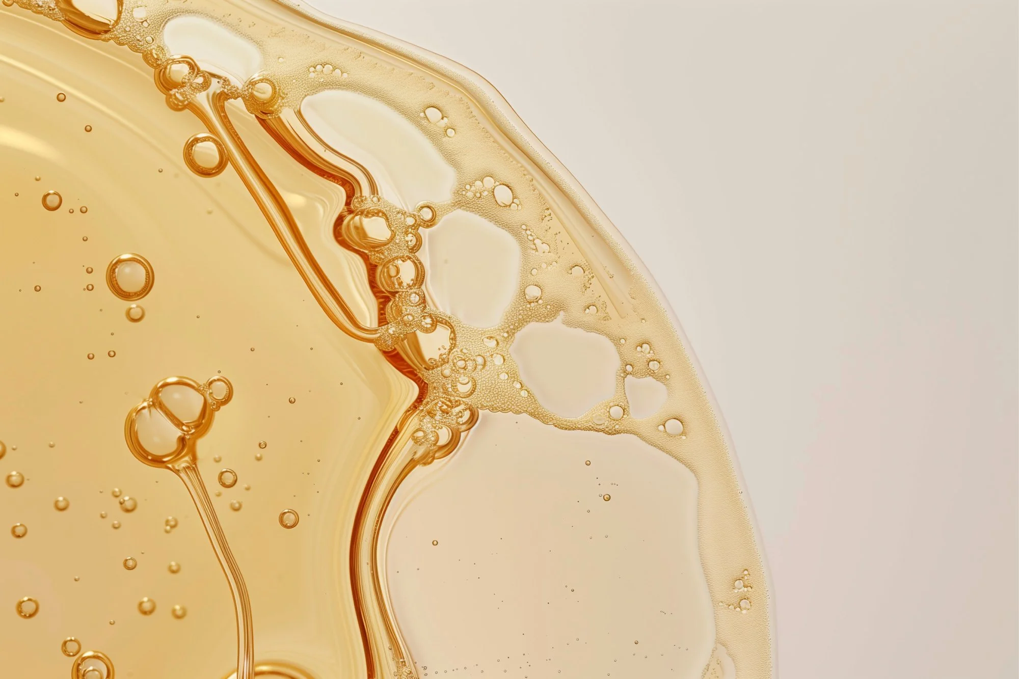 Close-up of a fizzy, golden liquid with bubbles on a light background.