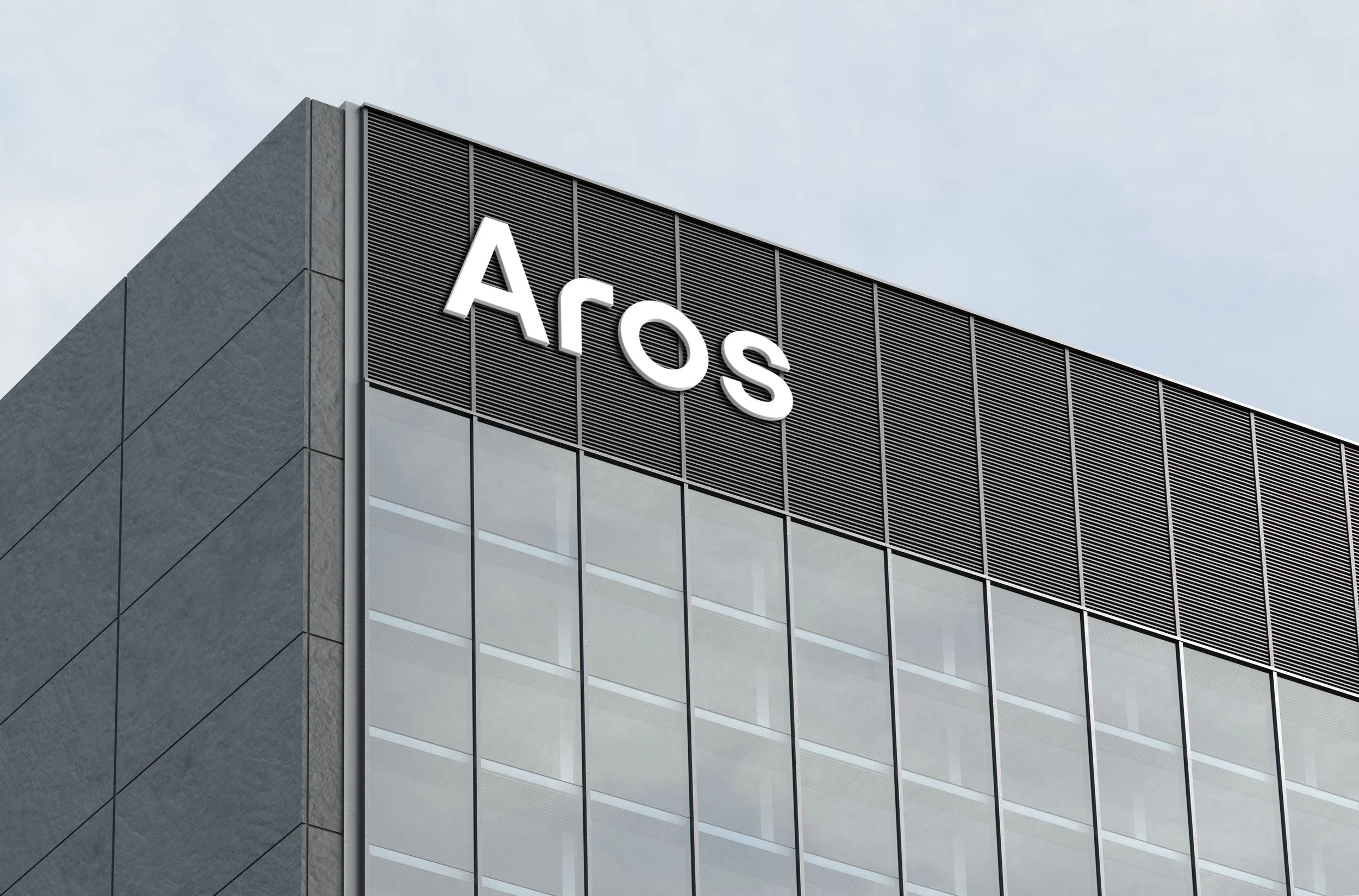 Close-up of the corner of a modern office building with the sign 'Aros' on the facade.