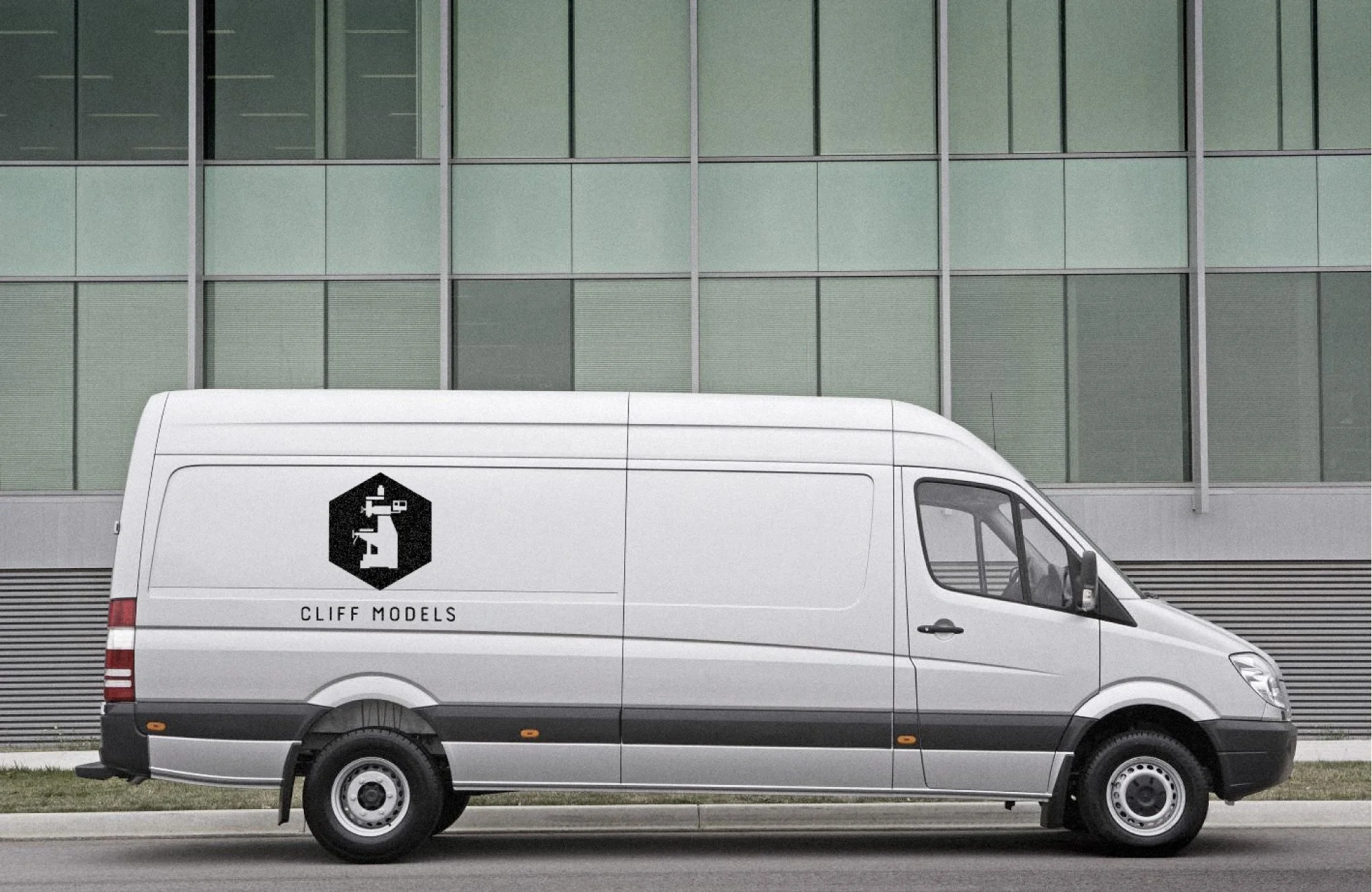 A white delivery van with the logo and name 'CLIFF MODELS' parked in front of a modern glass building.