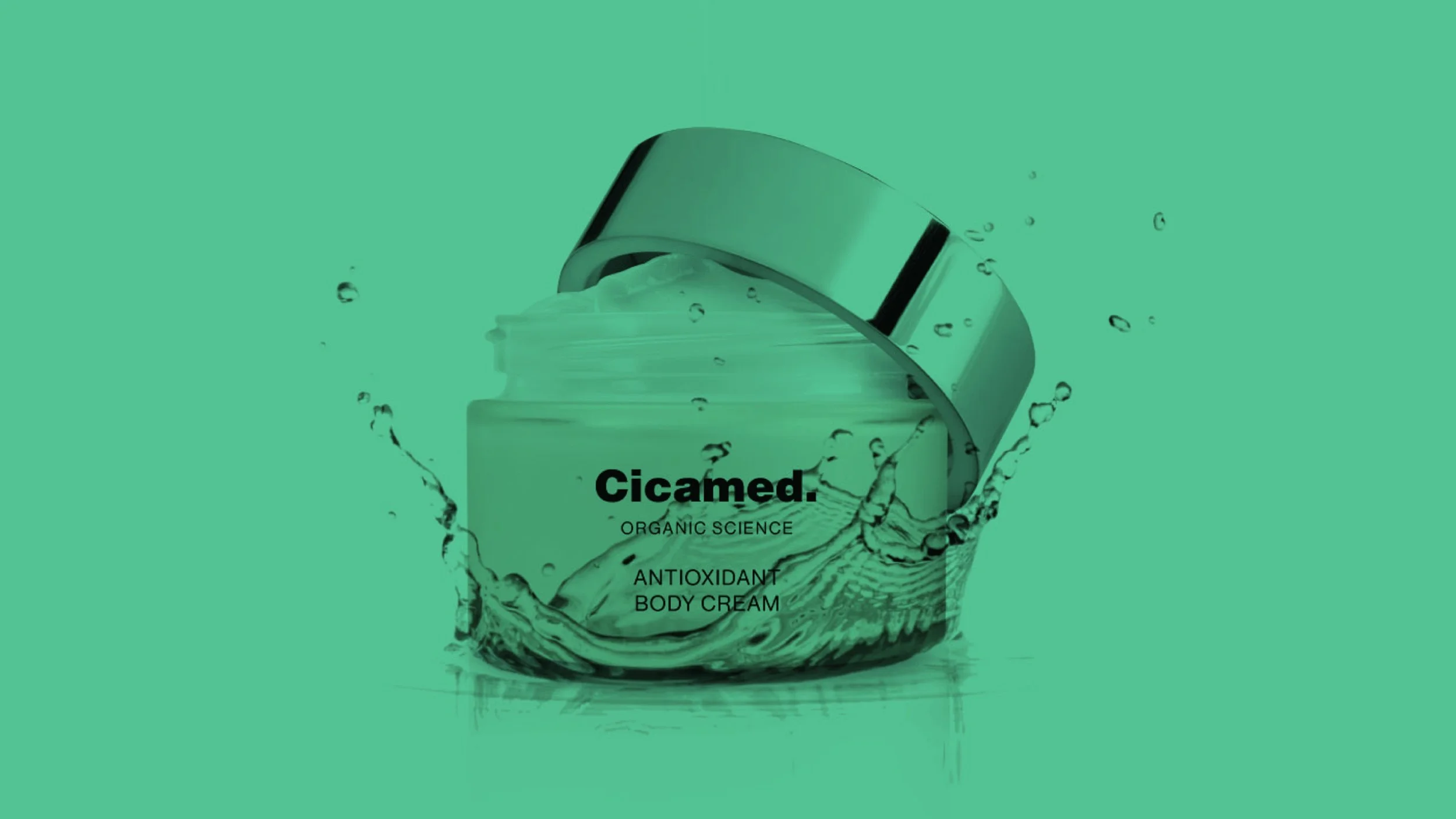 A green jar of CICAMED antioxidant body cream with the lid off, water splash effect, and black text on the jar label, set against a green background.