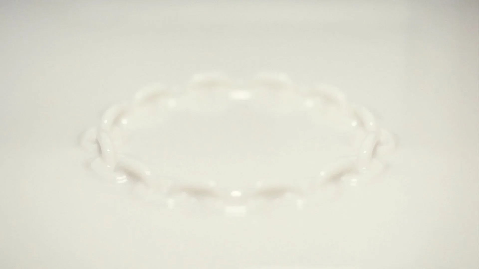 Close-up of a delicate, circular chain made of small, transparent beads or rings on a white background.