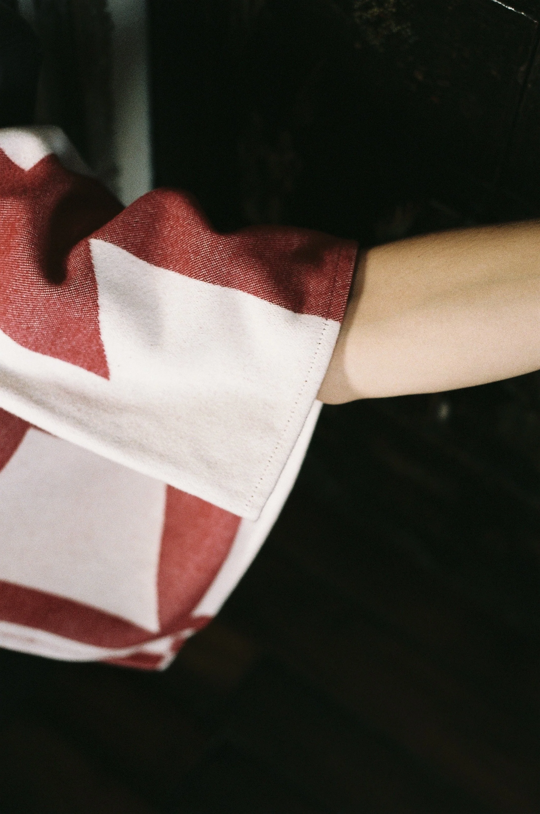 Close-up of a person wearing a red and white striped shirt with the sleeve rolled up.
