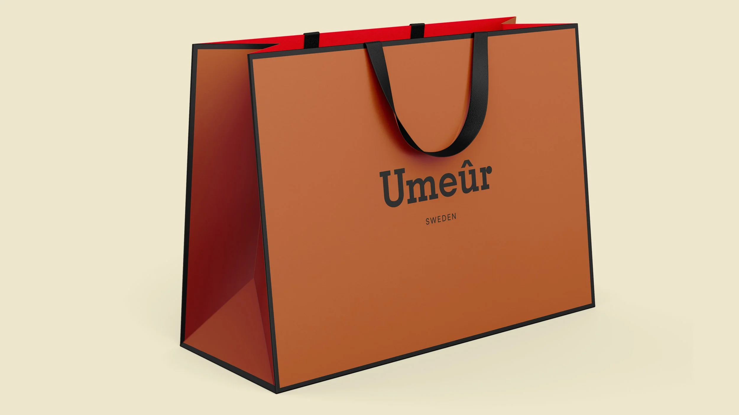 A large shopping bag with black handles, orange exterior, and red interior lining. The bag has the word 'Umeå' and 'Sweden' written on the front in black text.
