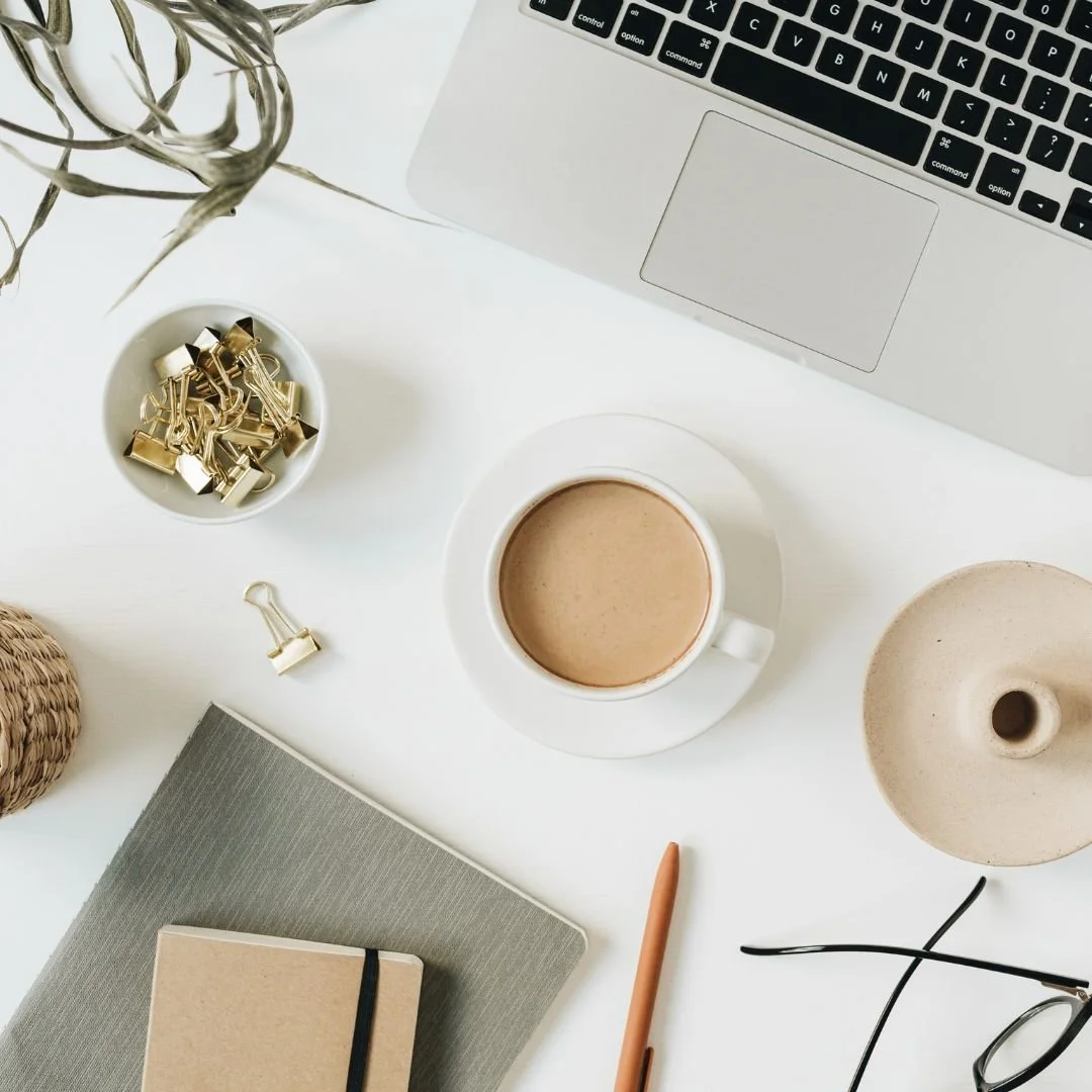 a flatlay photo of a cup of tea on a desk with a laptop and accessories