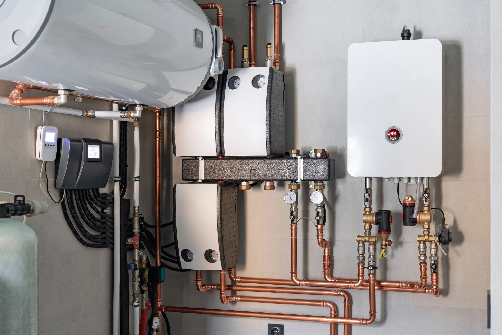 A wall-mounted heating system with a white tank, black and white components, copper pipes, gauges, and controls.