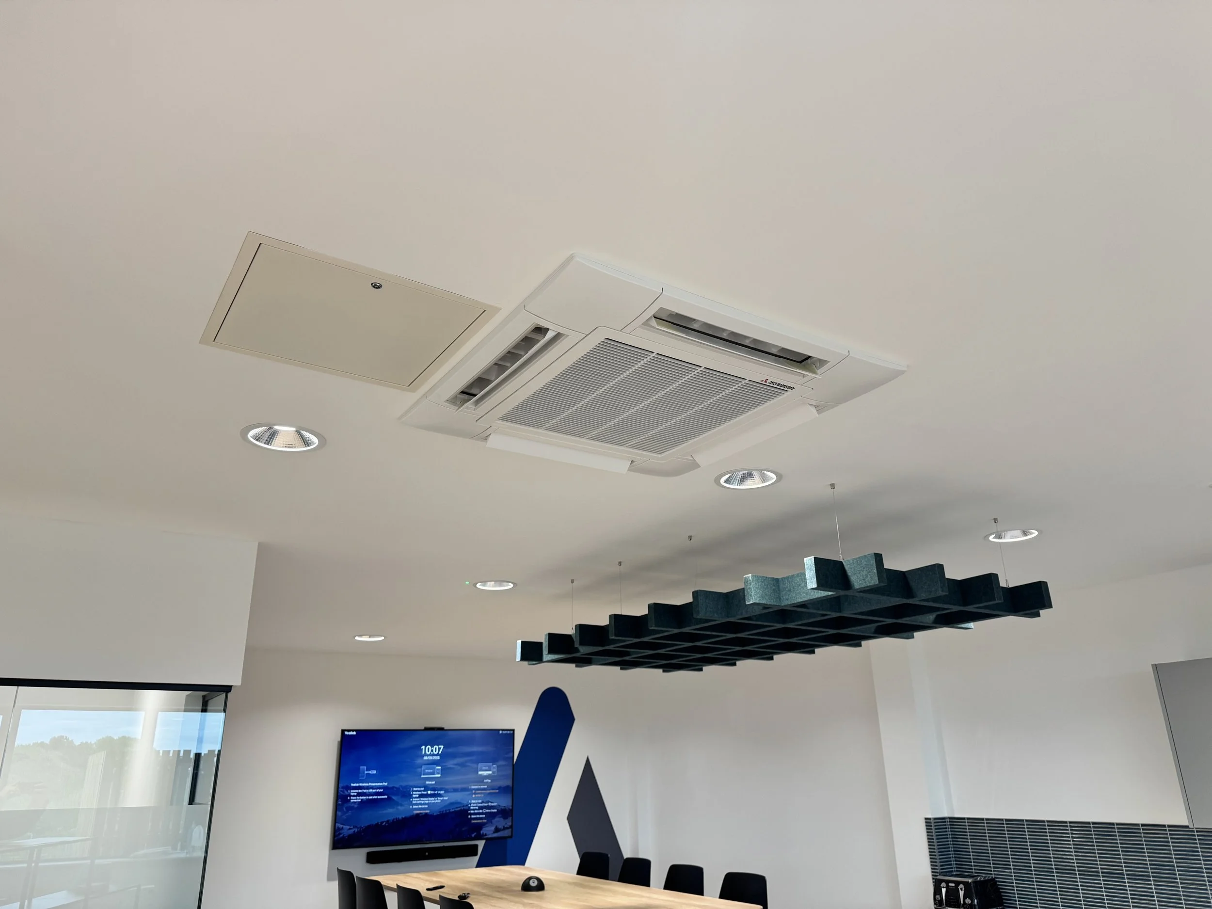 Ceiling with air conditioning unit, recessed lights, window, and modern decor in a conference room.