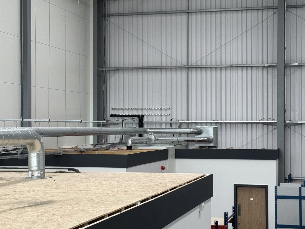 Industrial interior with metal pipes and a wooden counter in a warehouse or workshop setting.