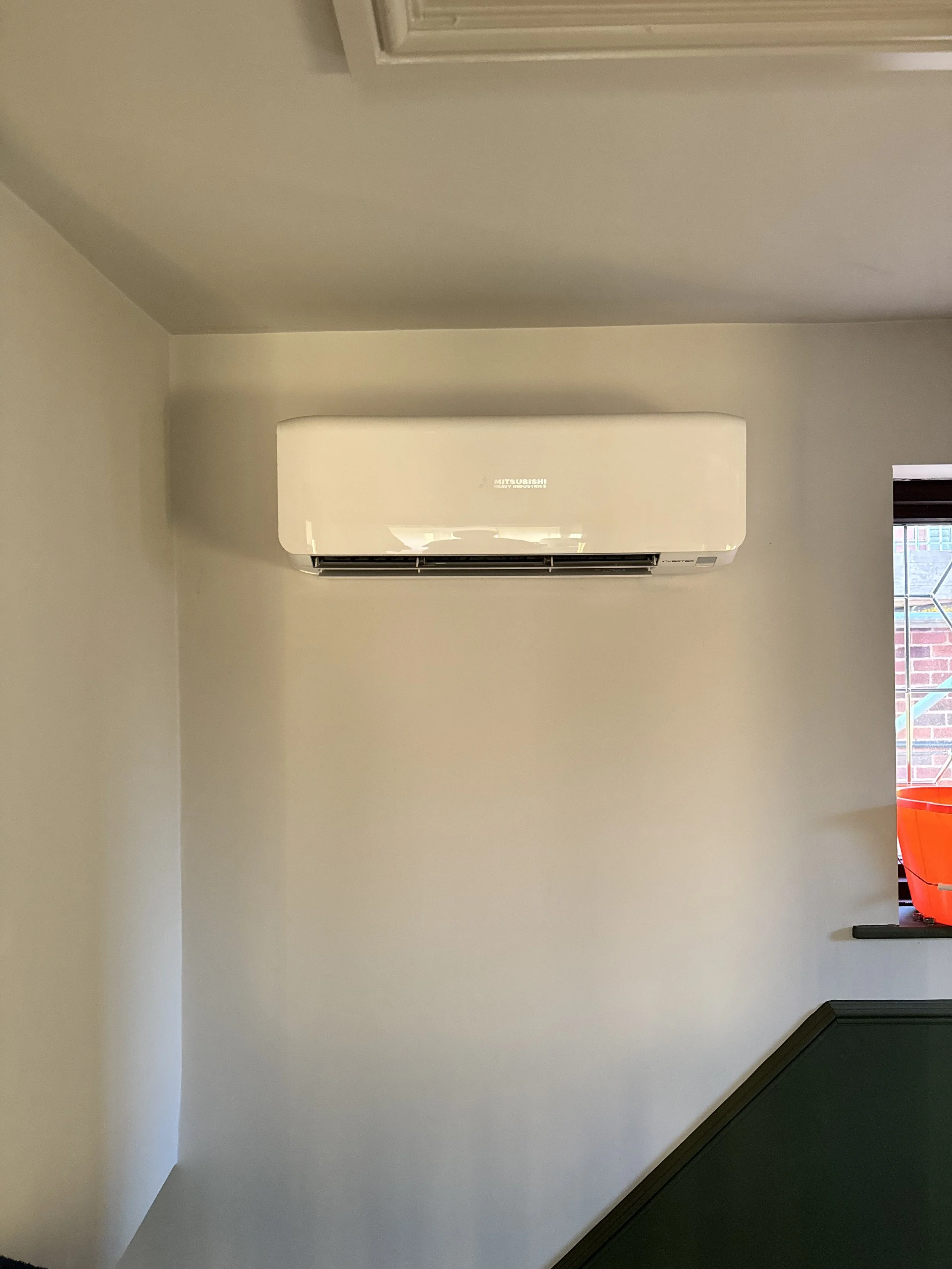 Wall-mounted Mitsubishi air conditioning unit in a room.