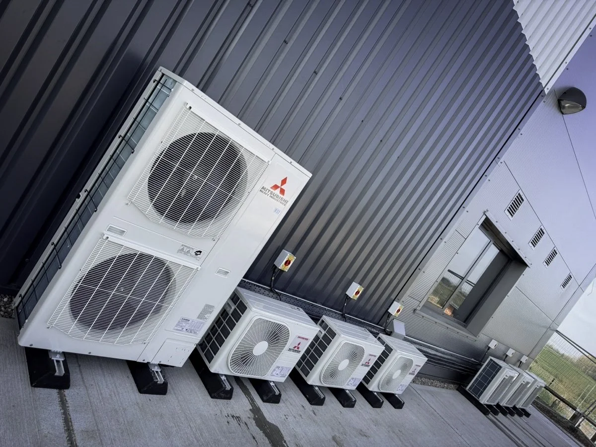 Multiple outdoor air conditioning units installed on a building exterior wall.