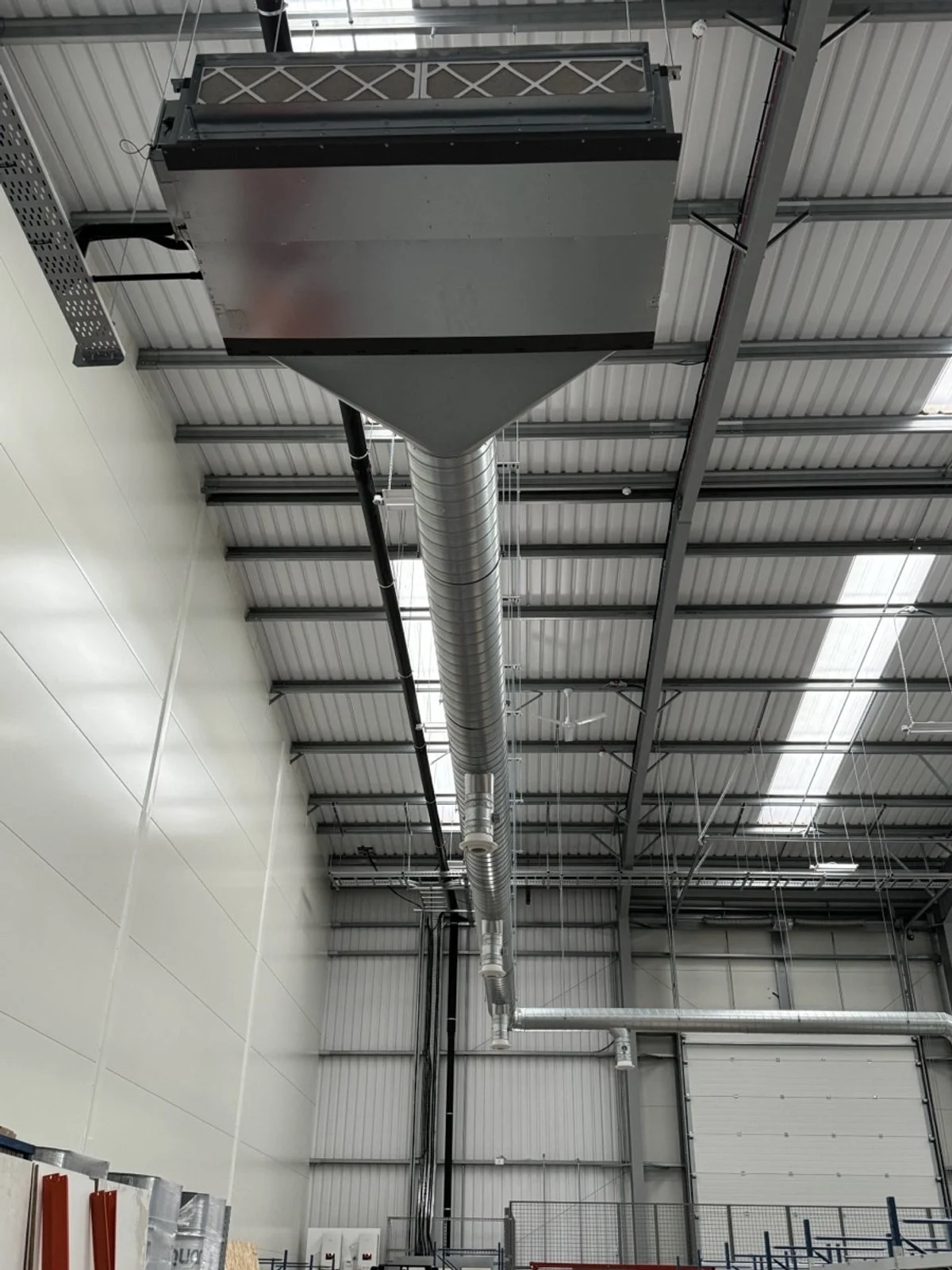 Industrial interior with large metal ventilation duct running along the ceiling.