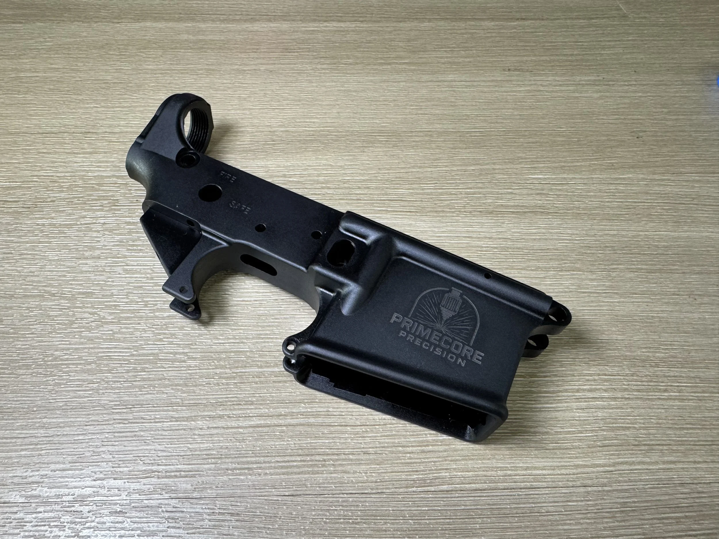 Custom AR15 lower receiver engraving with Aluma Black refinishing for a darker, factory-style appearance after laser marking. Services include NFA engraving, selector markings, clone-correct engravings, logos, serial engraving, and custom text. Prime