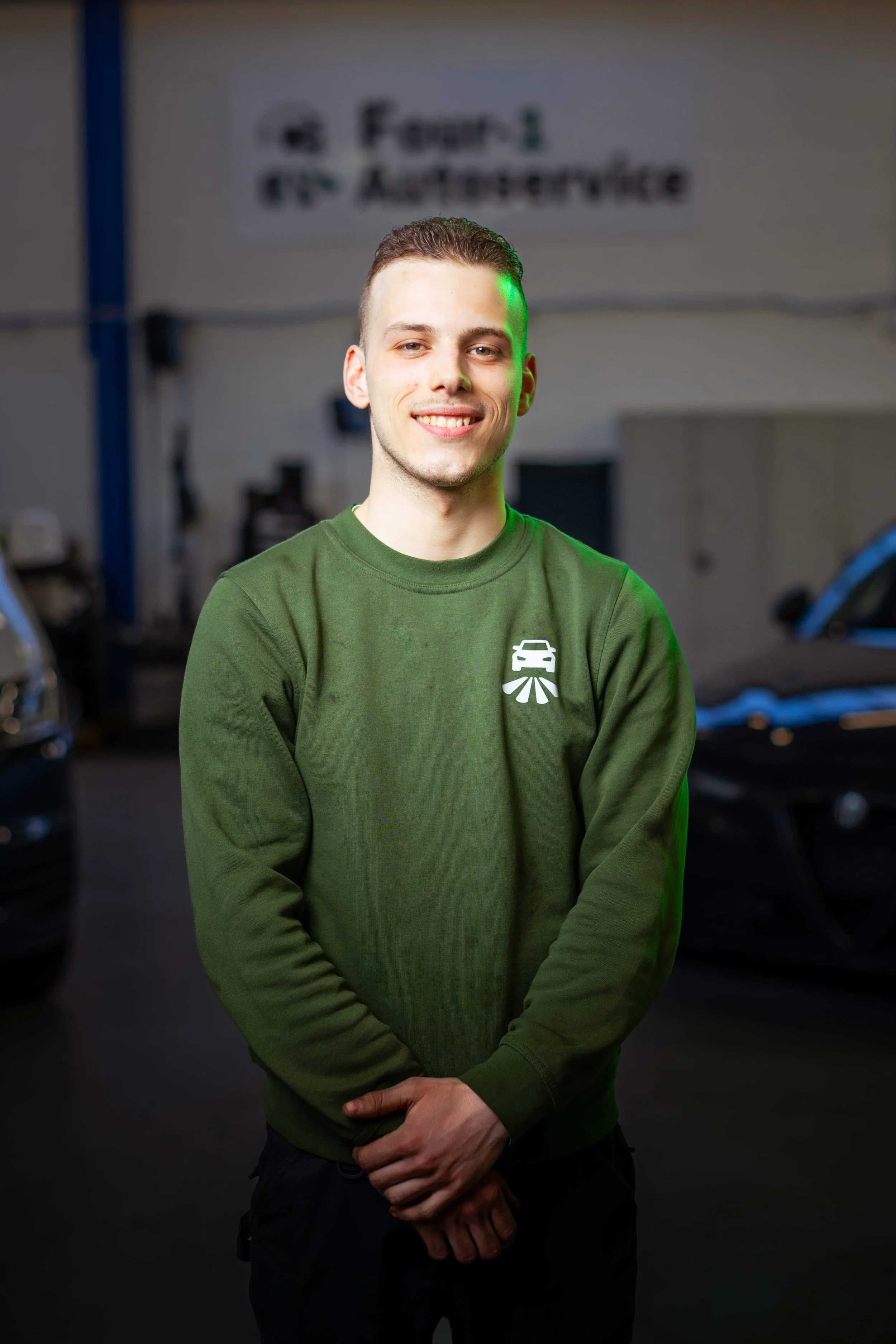 A woman with shoulder-length black hair smiling in a botanical setting with green plants around her.