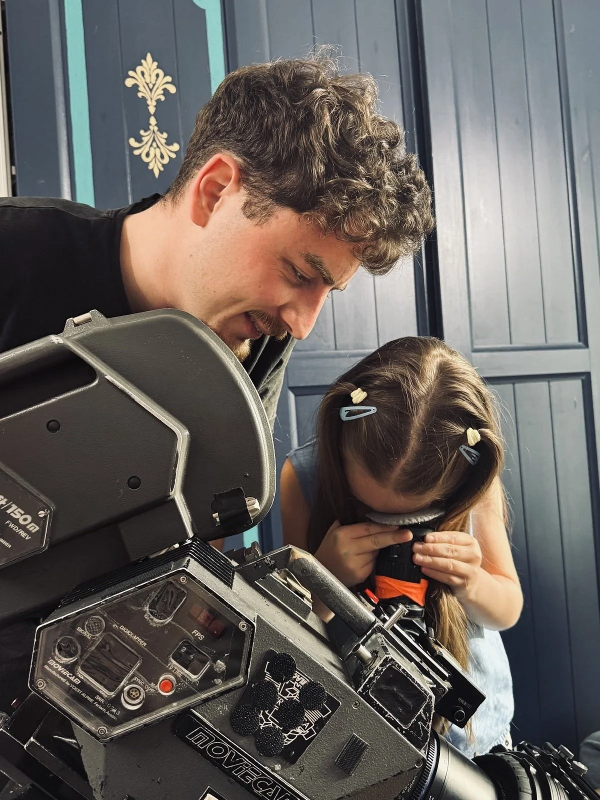 A man and a young girl looking through a professional camera.