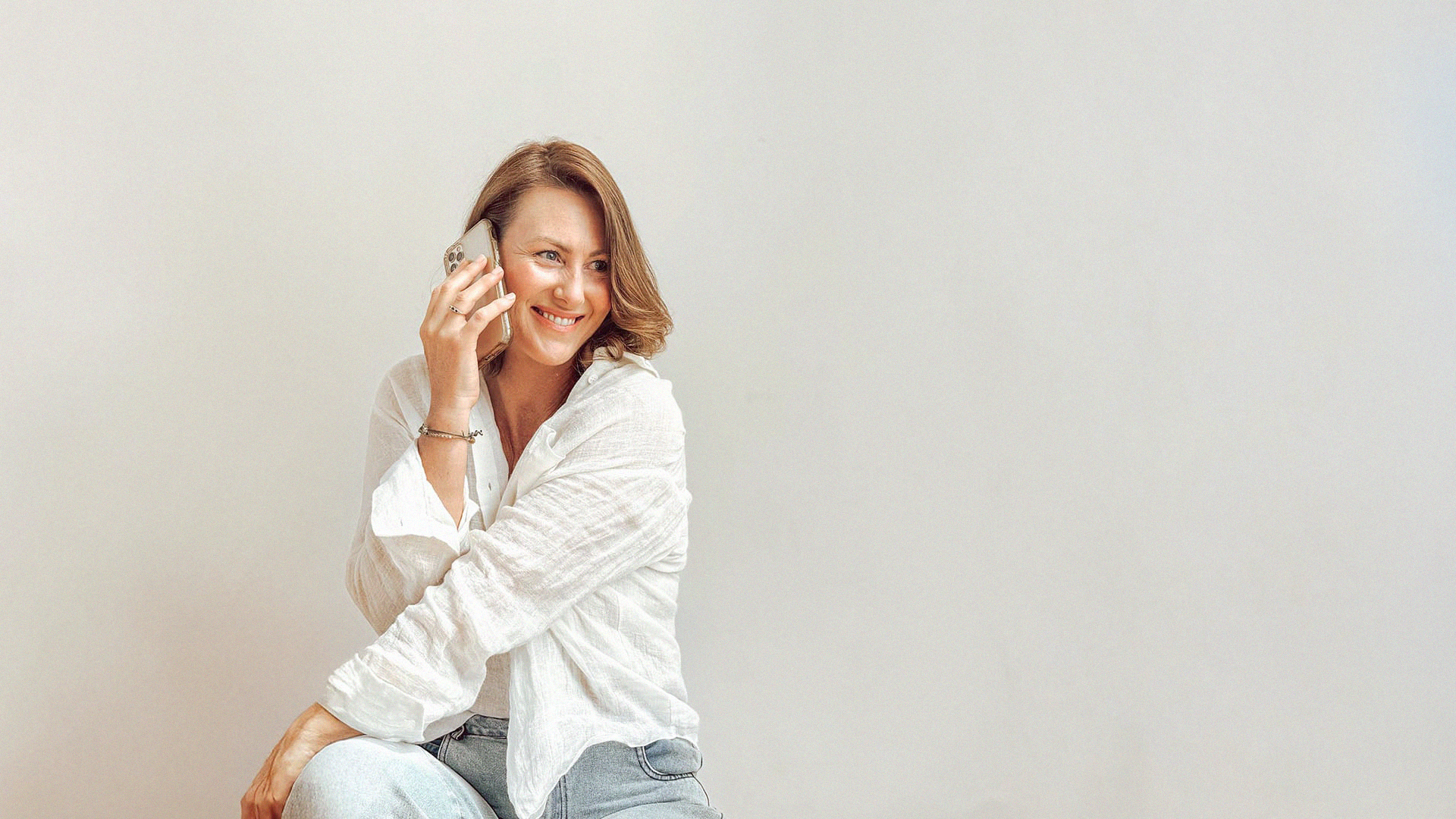 Portrait of Lauren Rosser, Meta Ads Strategist talking on a mobile phone, wearing a white linen shirt and smiling.