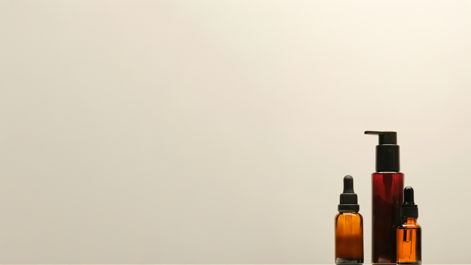 Three dropper bottles with black caps, one large red pump bottle, and two small orange bottles, arranged on a plain white background.
