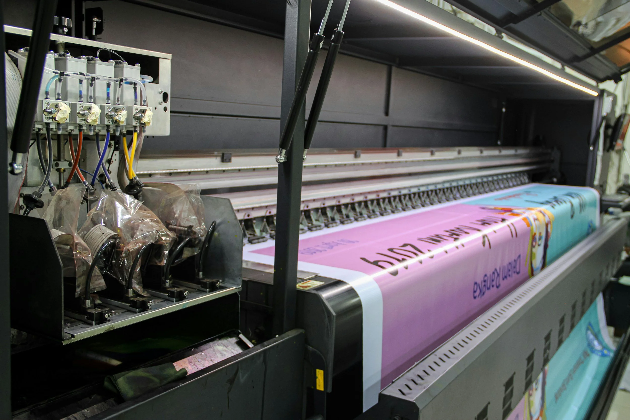 Large digital printer printing a colorful banner with text and graphics.