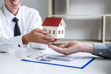 A person handing over a small model house to another person in a professional setting.