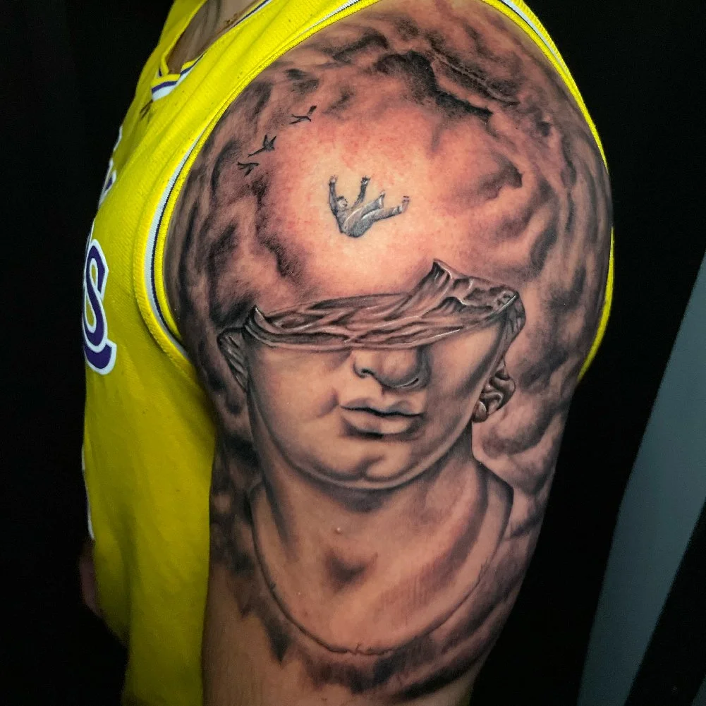 Surreal tattoo of a human falling from the sky into an open head of a marble-carved greek-style statue.