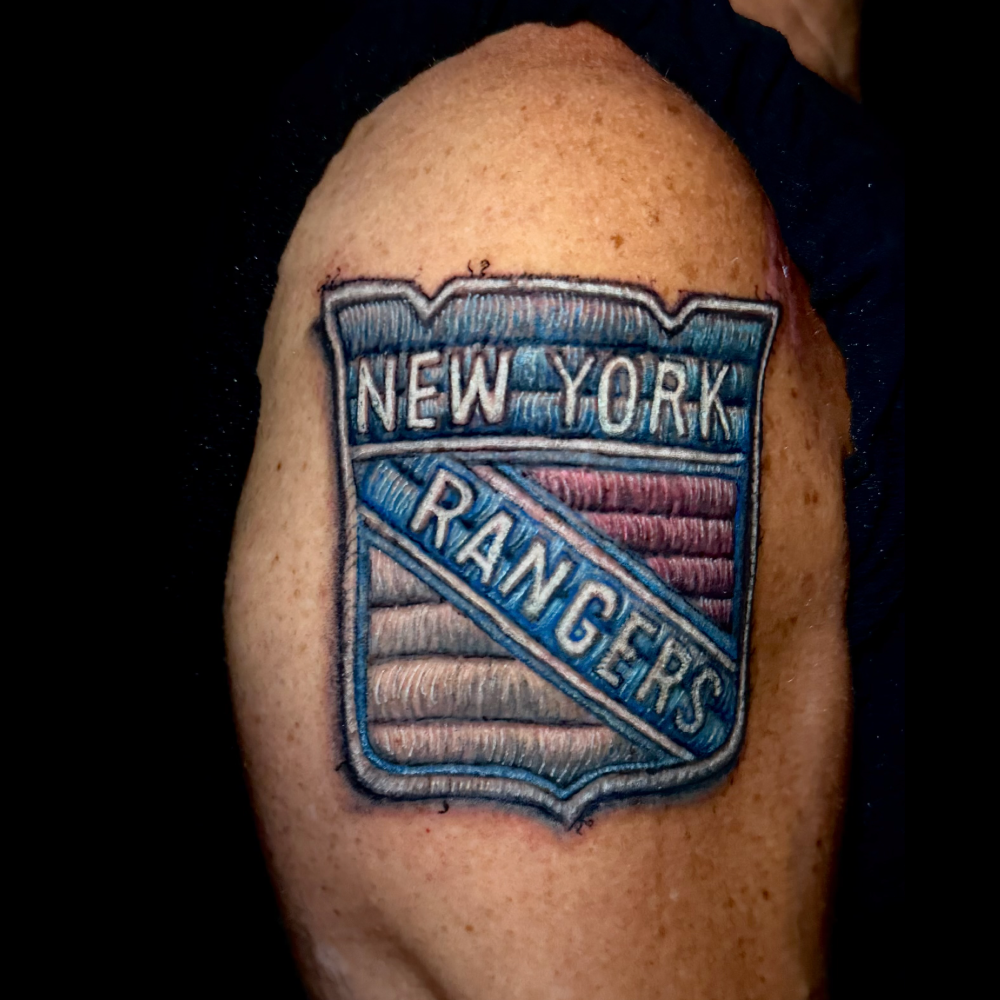 Patchwork tattoo on someone's arm of the New York Rangers NHL logo. The tattoo gives the impression that it was stitched as opposed to a standard-style tattoo.