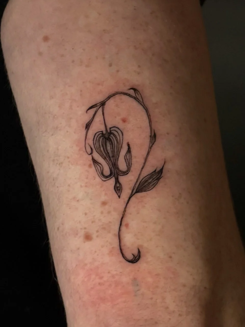 Fine line tattoo of an abstract flower.