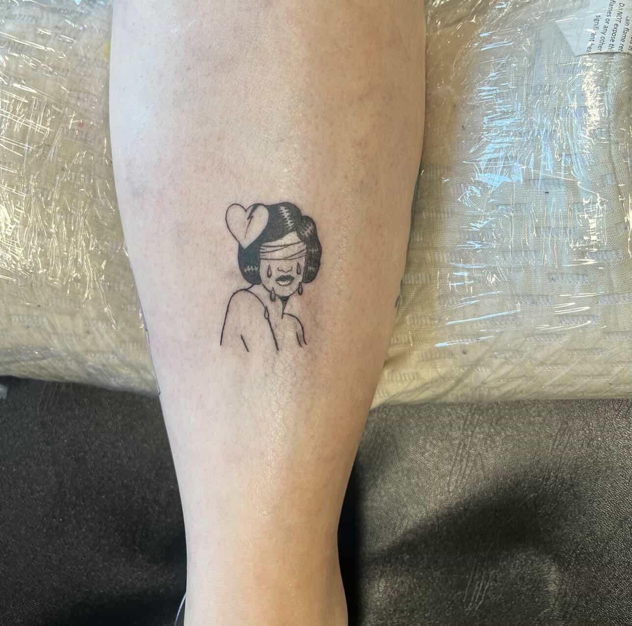 Tattoo of a blindfolded woman crying with a broken heart.
