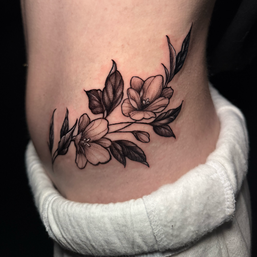 Tattoo of a floral adornment on someone's waist.