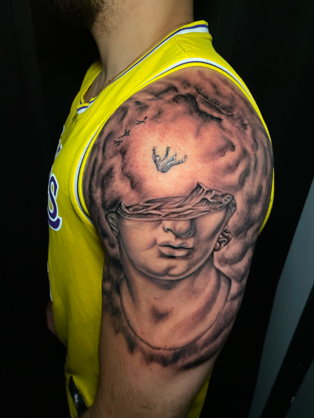 Surreal tattoo of a human falling from the sky into an open head of a marble-carved greek-style statue.