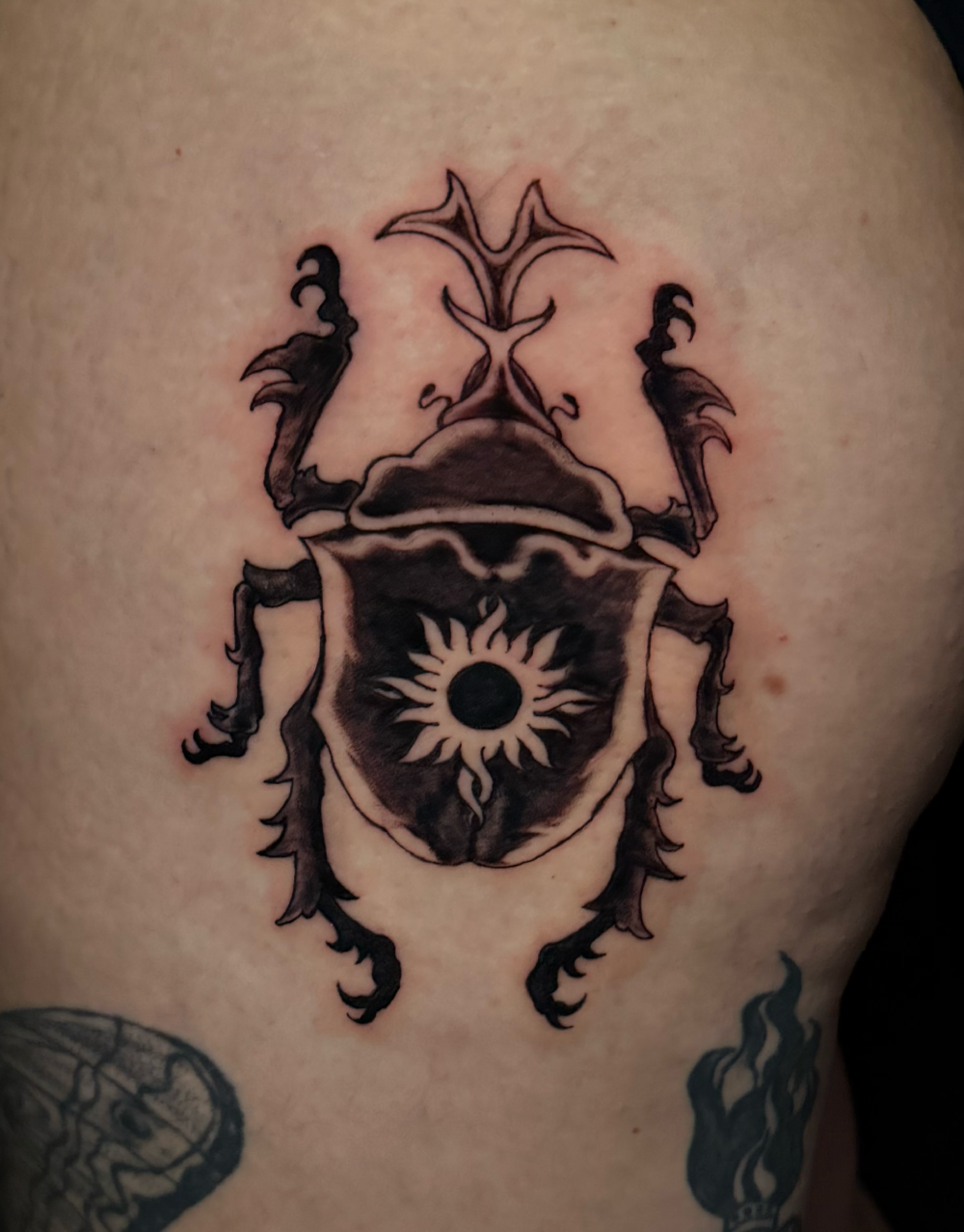 Detailed scarab beetle tattoo with dark shading.