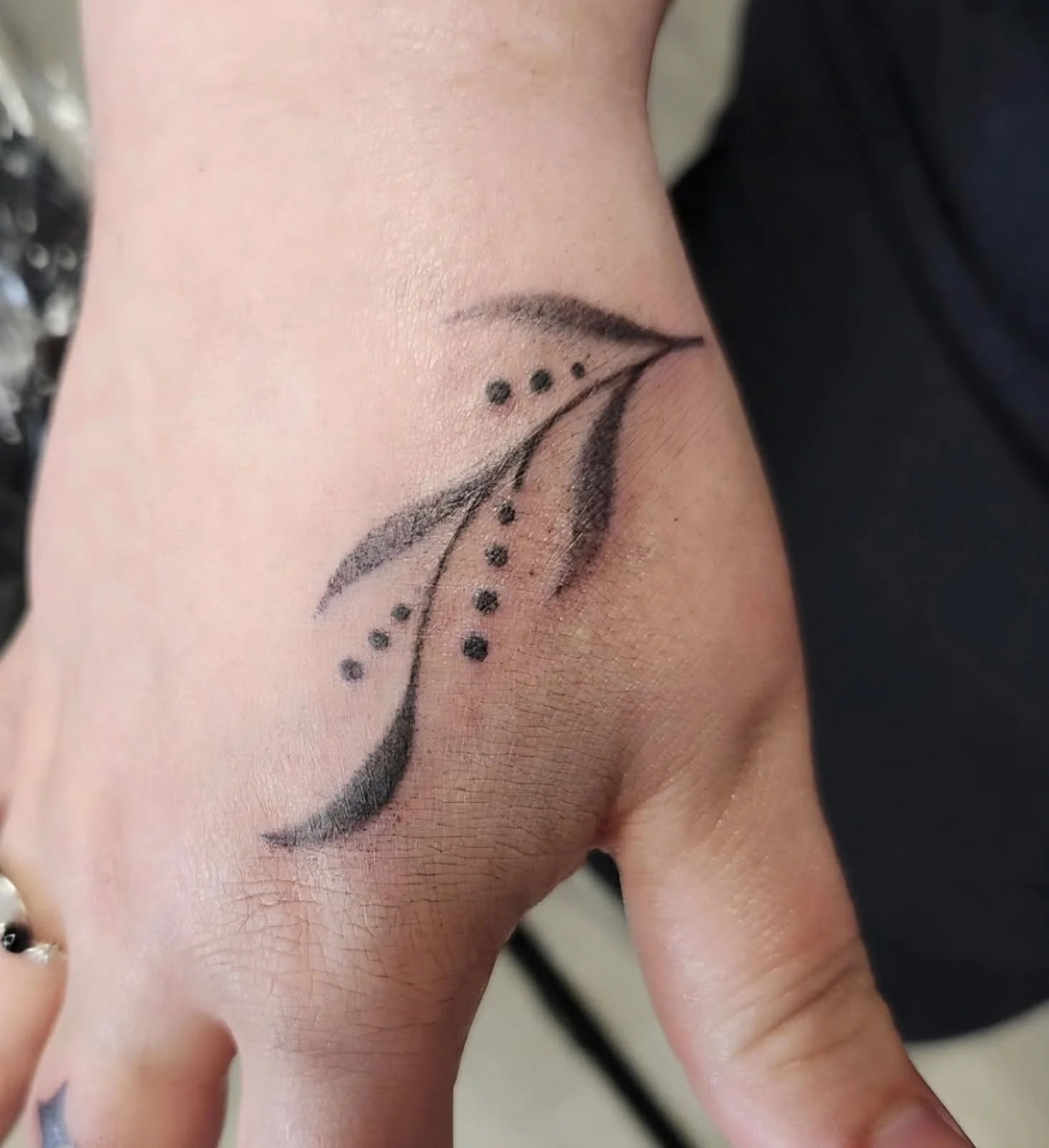 Abstract floral hand tattoo with dots.