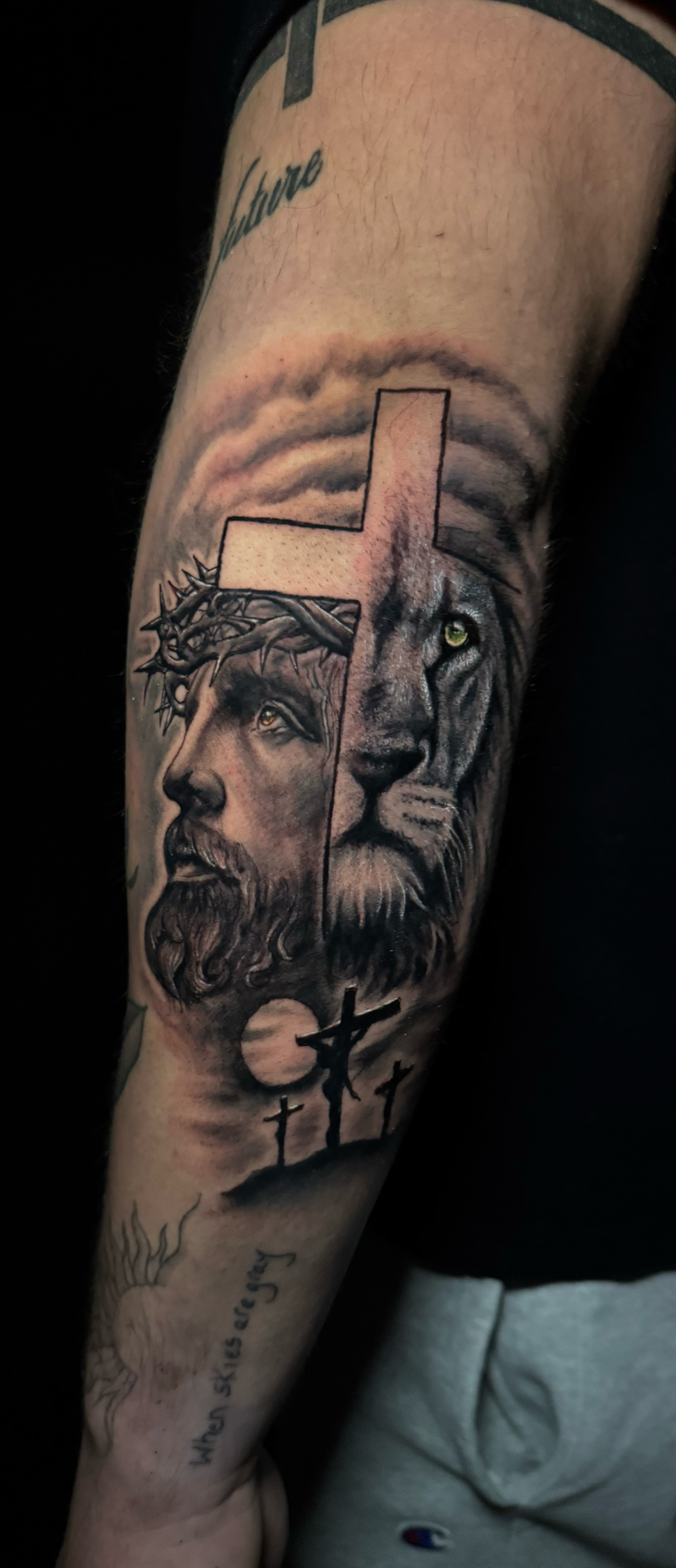 Black and white tattoo of Jesus Christ mixed in with a lion and a cross.