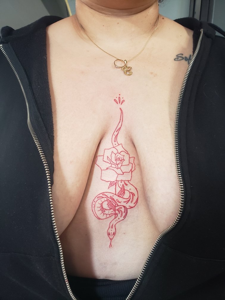 Red tattoo of a snake slithering through a flower.