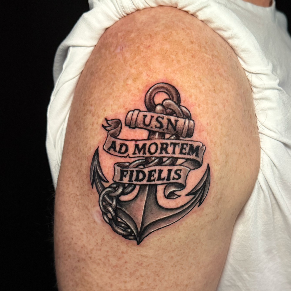 Anchor tattoo on someone's right arm. Showcasing text on a banner around the anchor.