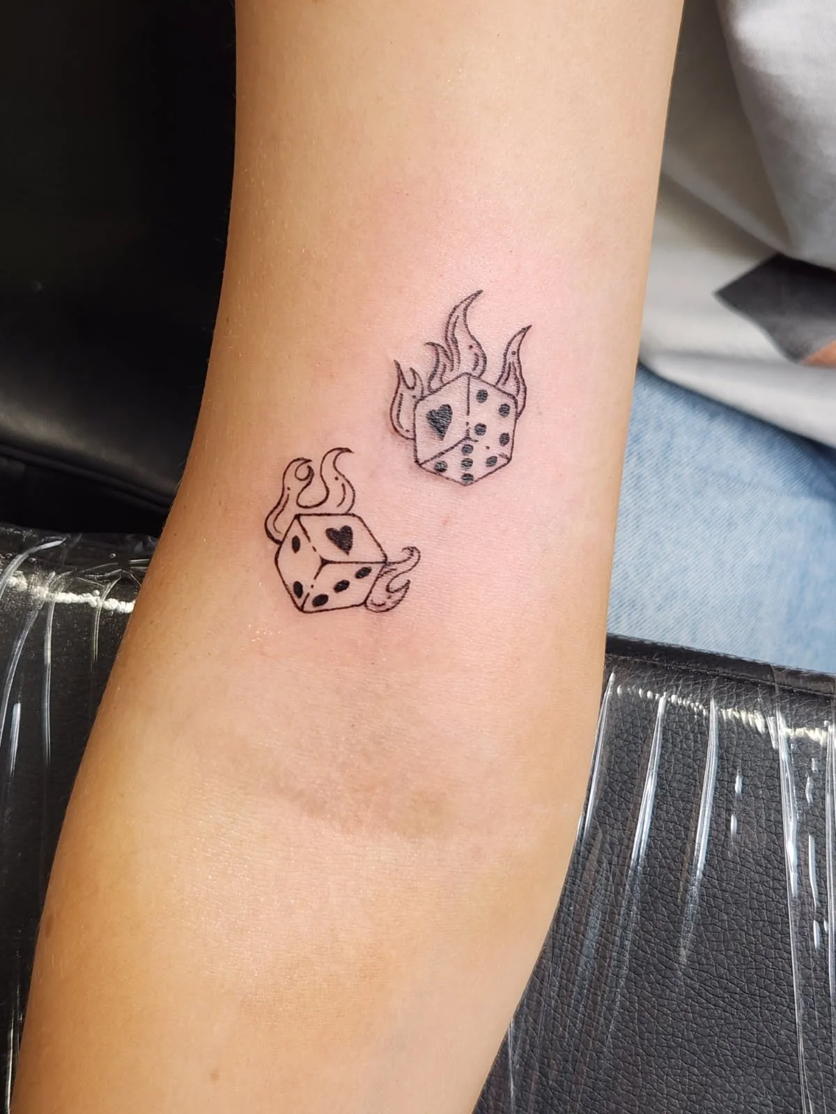 Pair of a dice tattoo that is aflame and has single hearts as the ones.