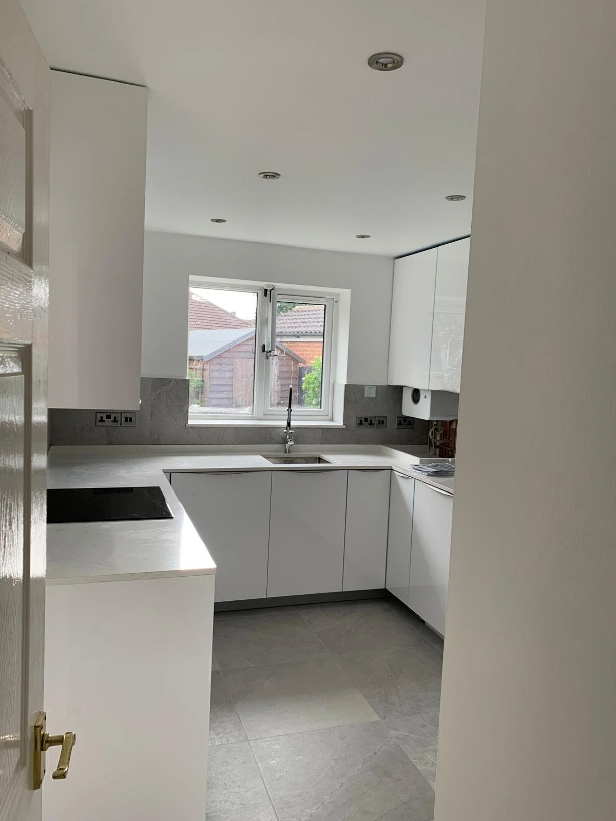 Modern white kitchen with a window, countertop, and cabinets.