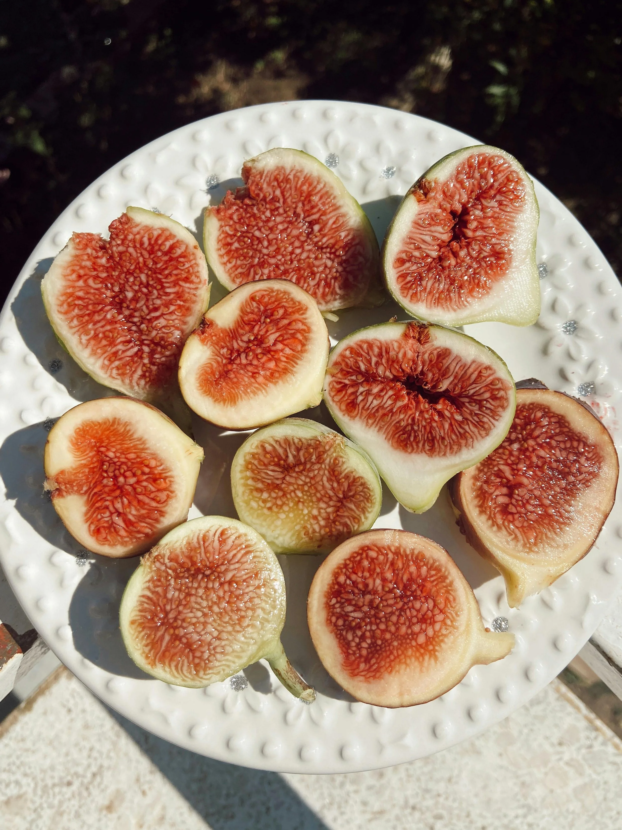 Several halves of fresh figs with red interiors on a white decorative plate.