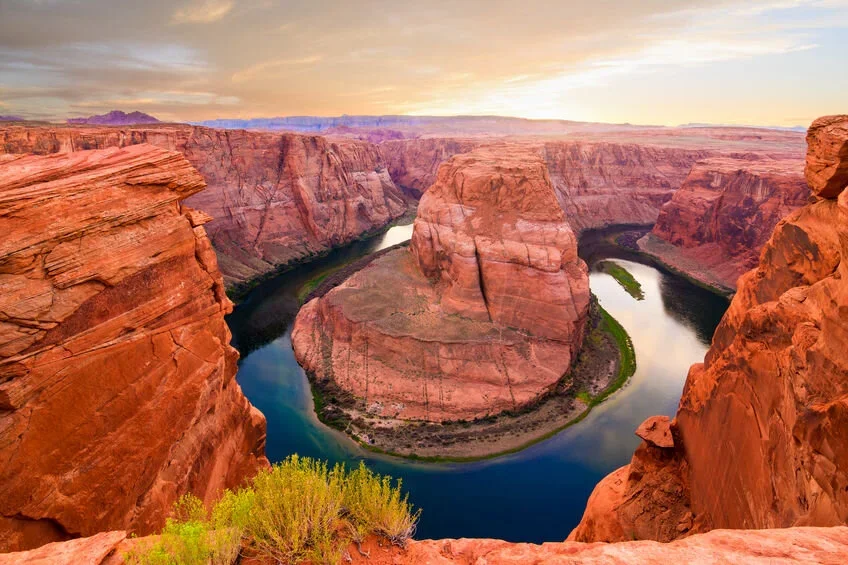 Aerial view of the Horseshoe Bend at sunset, featuring red rock formations and a winding river.