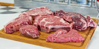 Assorted raw red meat steaks on a wooden cutting board