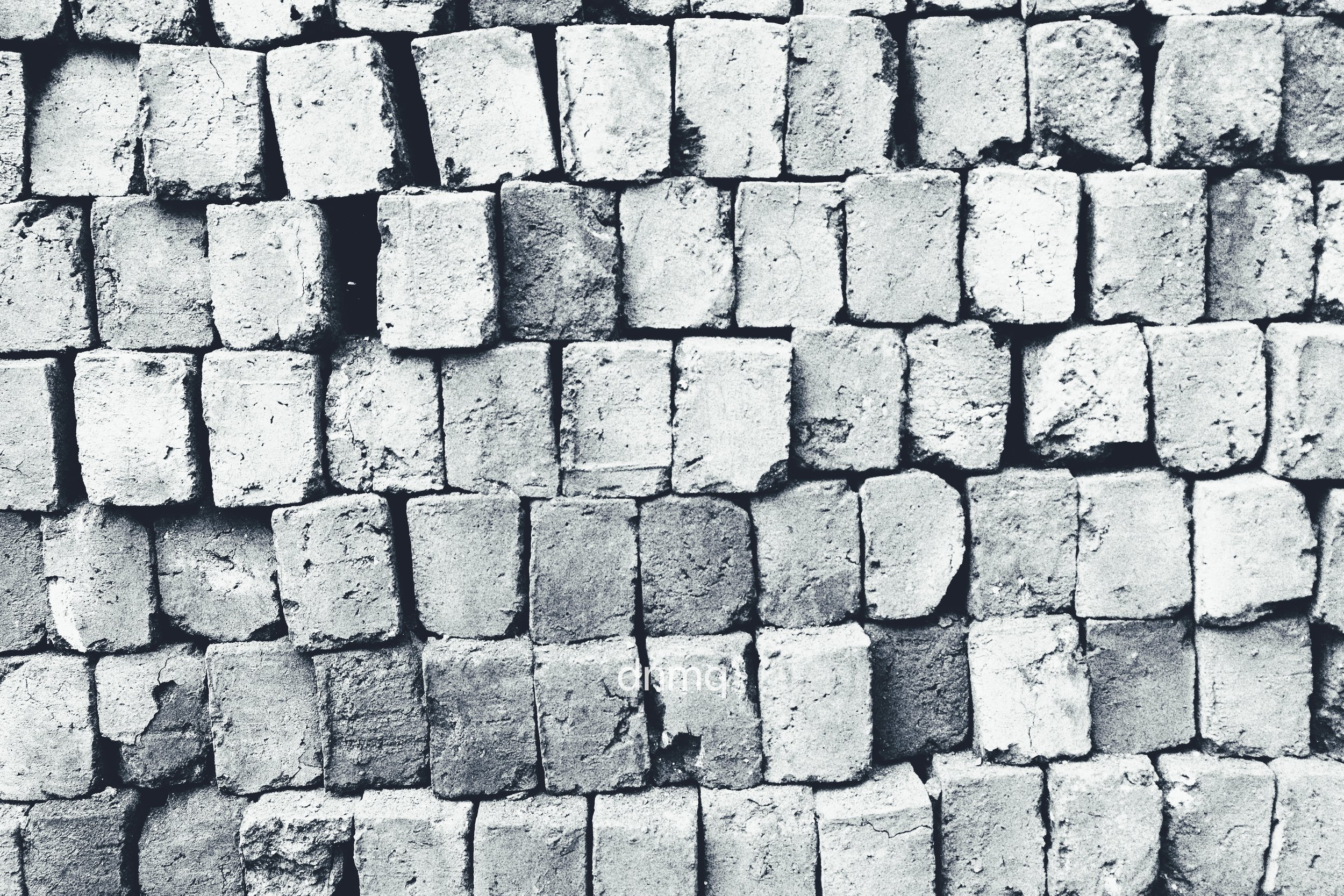 Pile of small, weathered concrete blocks stacked together in a wall.