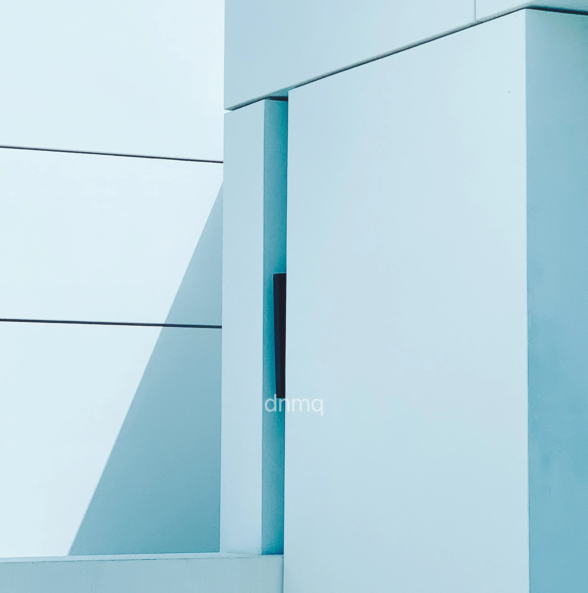 Close-up of a modern, minimalist white building with geometric lines and shadows.