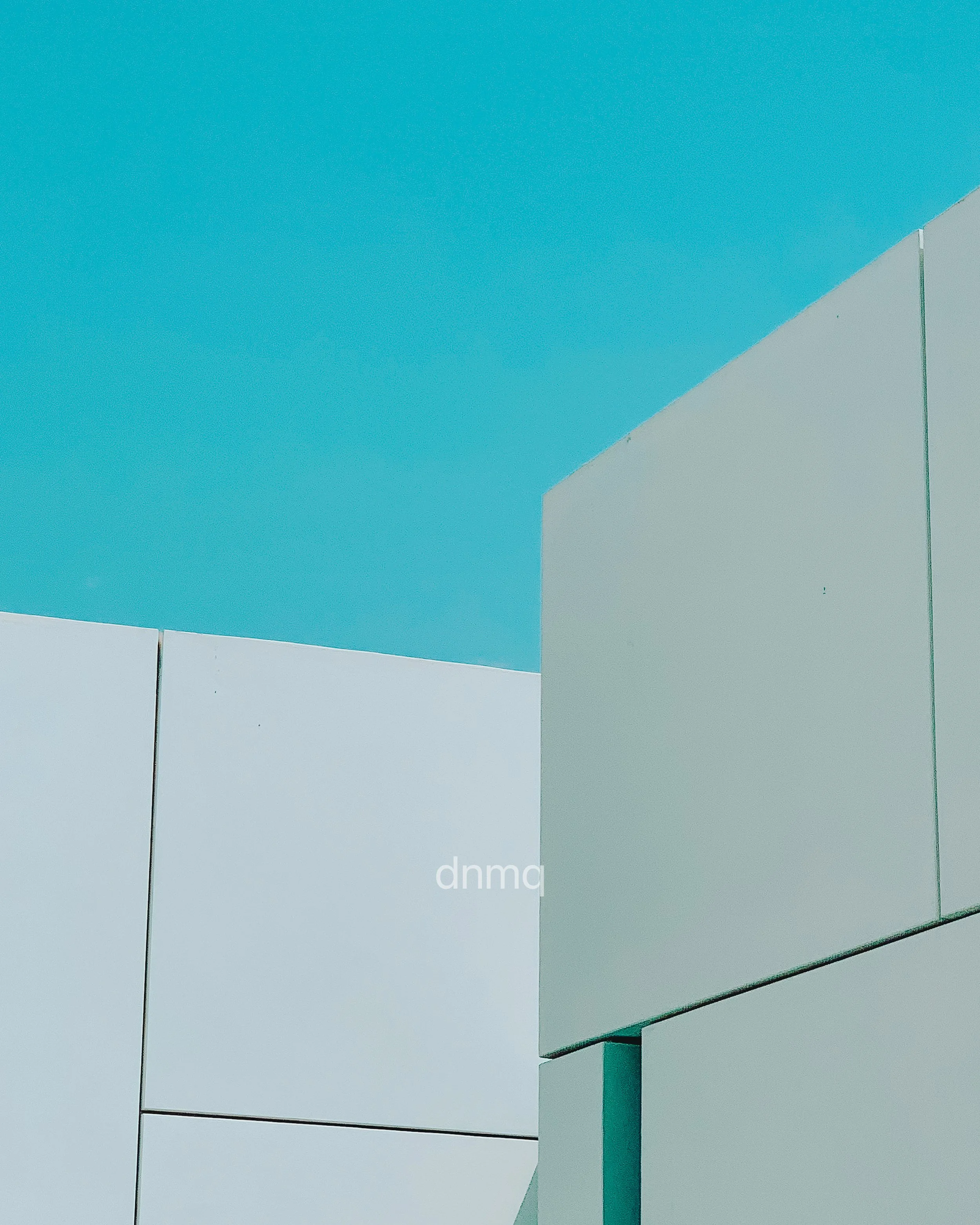 Modern white building with geometric shapes and clean lines against a clear blue sky.