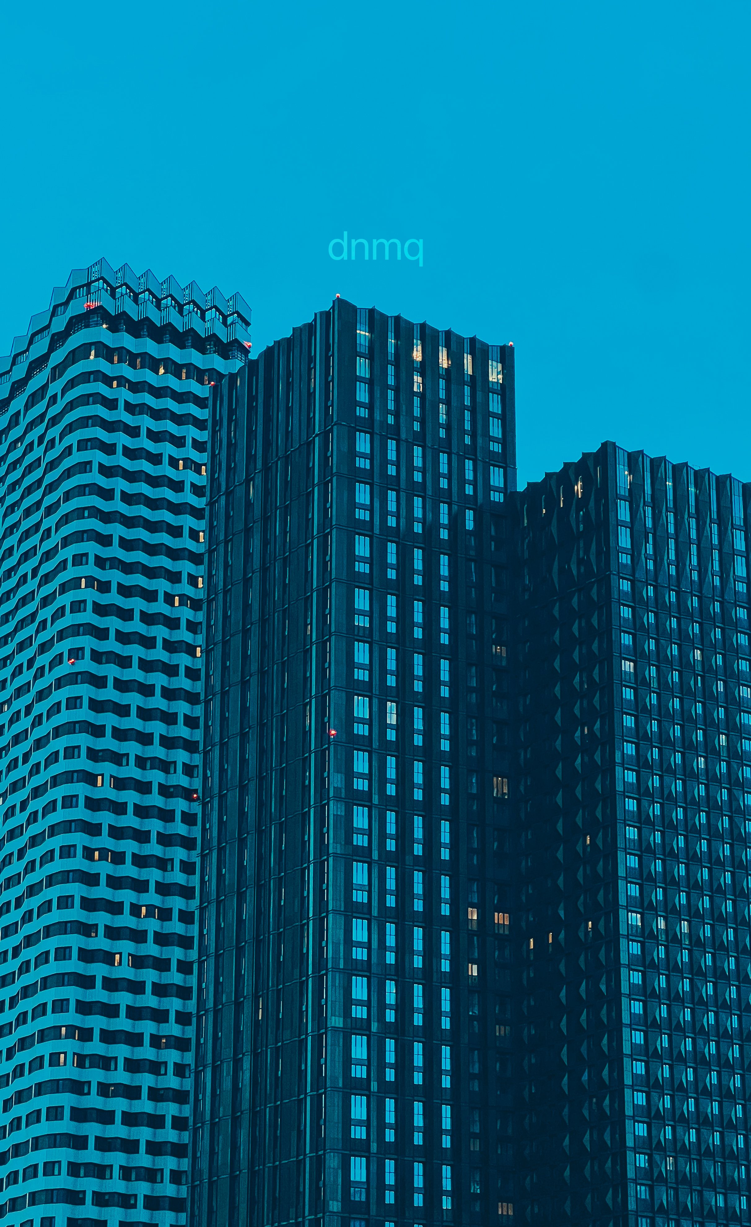 Tall modern office buildings with glass facades against a blue sky in an urban cityscape.