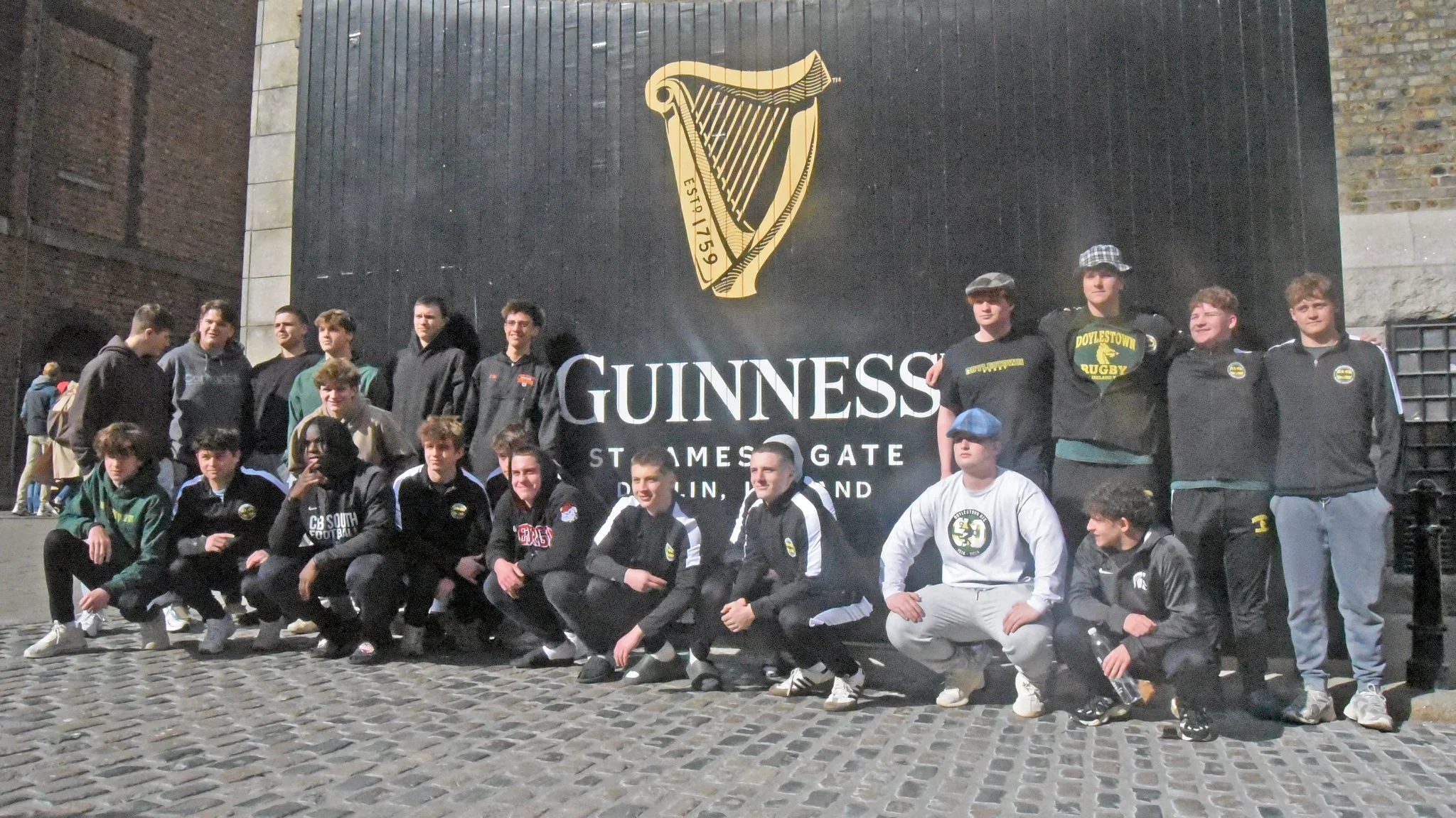 A group of young rugby players posing in front of a Guinness sign at the St. James Gate Brewery in Dublin, Ireland.