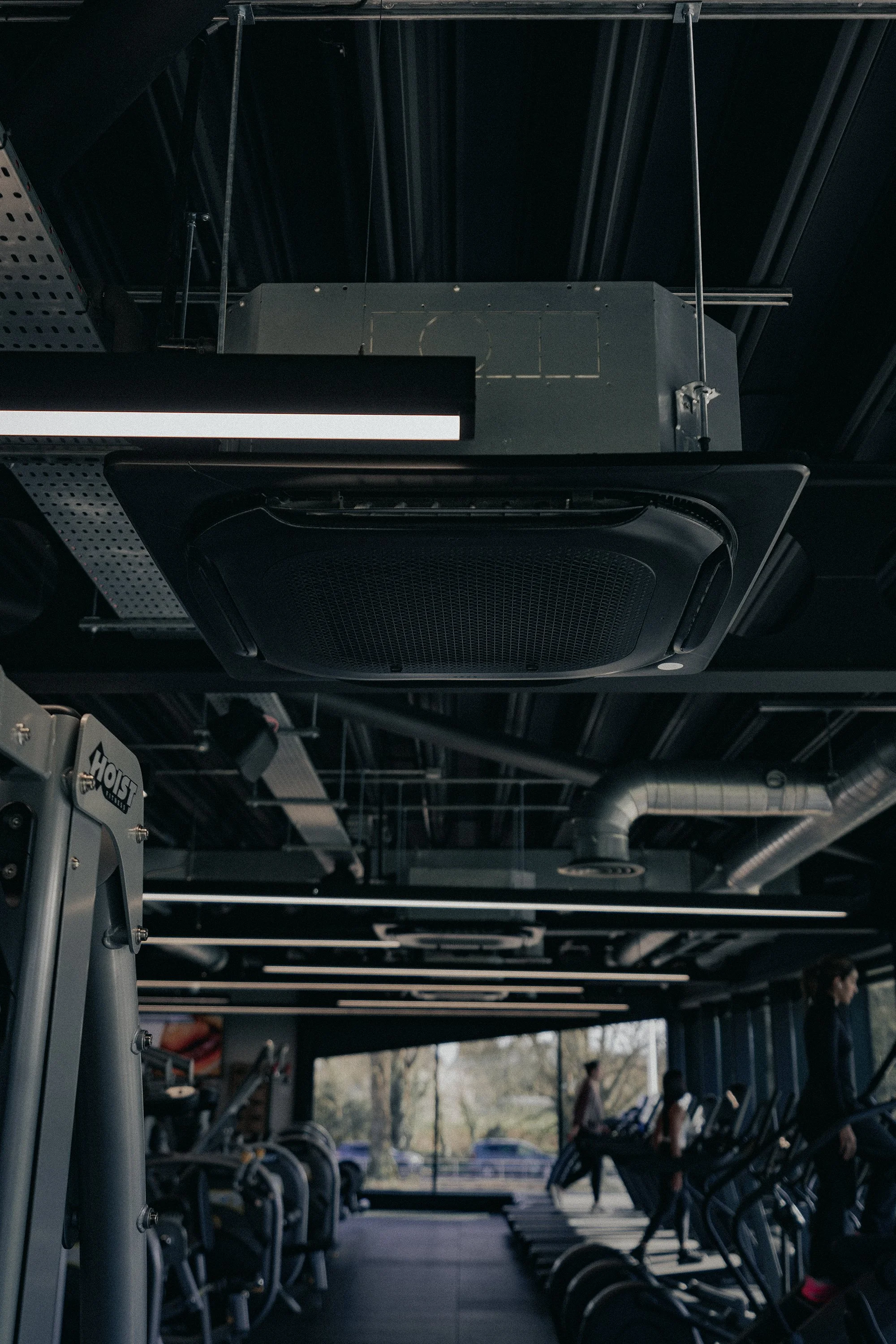 Inside a gym with black ceiling and equipment, showing a top of the range MVHR ventilation system.