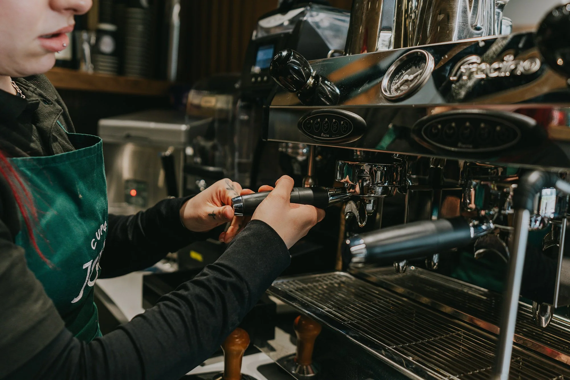A person operating a the espresso machine in at Cup of Joy wellness café.