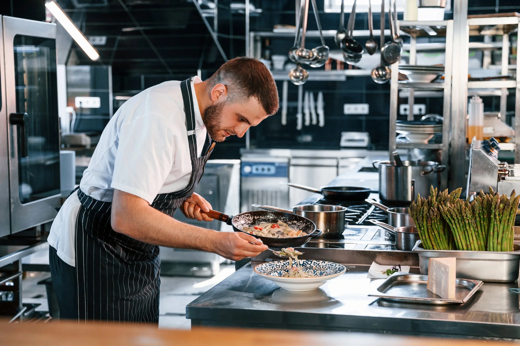 A chef in a professional kitchen plating food.