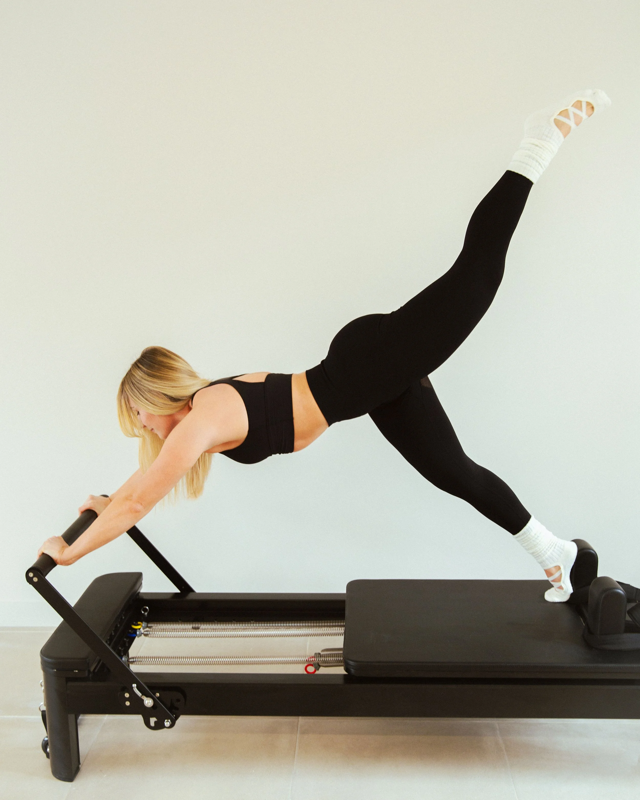 Femme faisant de l'exercice sur un appareil de fitness, en position de planche avec une jambe levée.